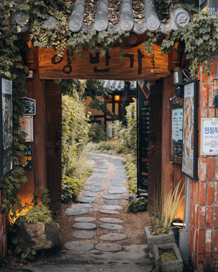Scenic view of a traditional Korean gate leading to a lush garden path in Jeonju